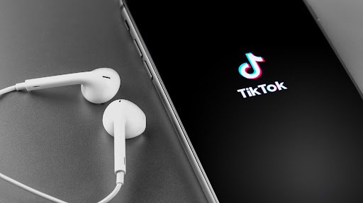 TikTok logo on the screen iPhone with Earpods. TikTok is app to create and share videos. Moscow, Russia - May 22, 2019